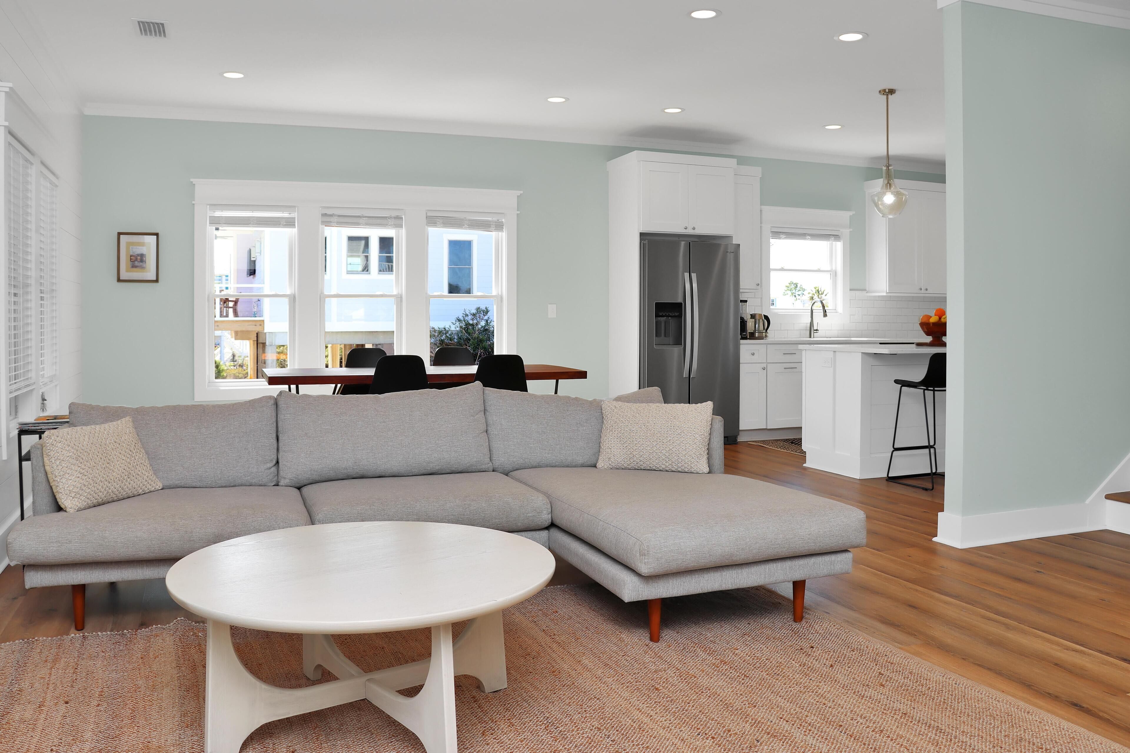 A modern living room with a sectional sofa, a round coffee table, and a kitchen in the background.