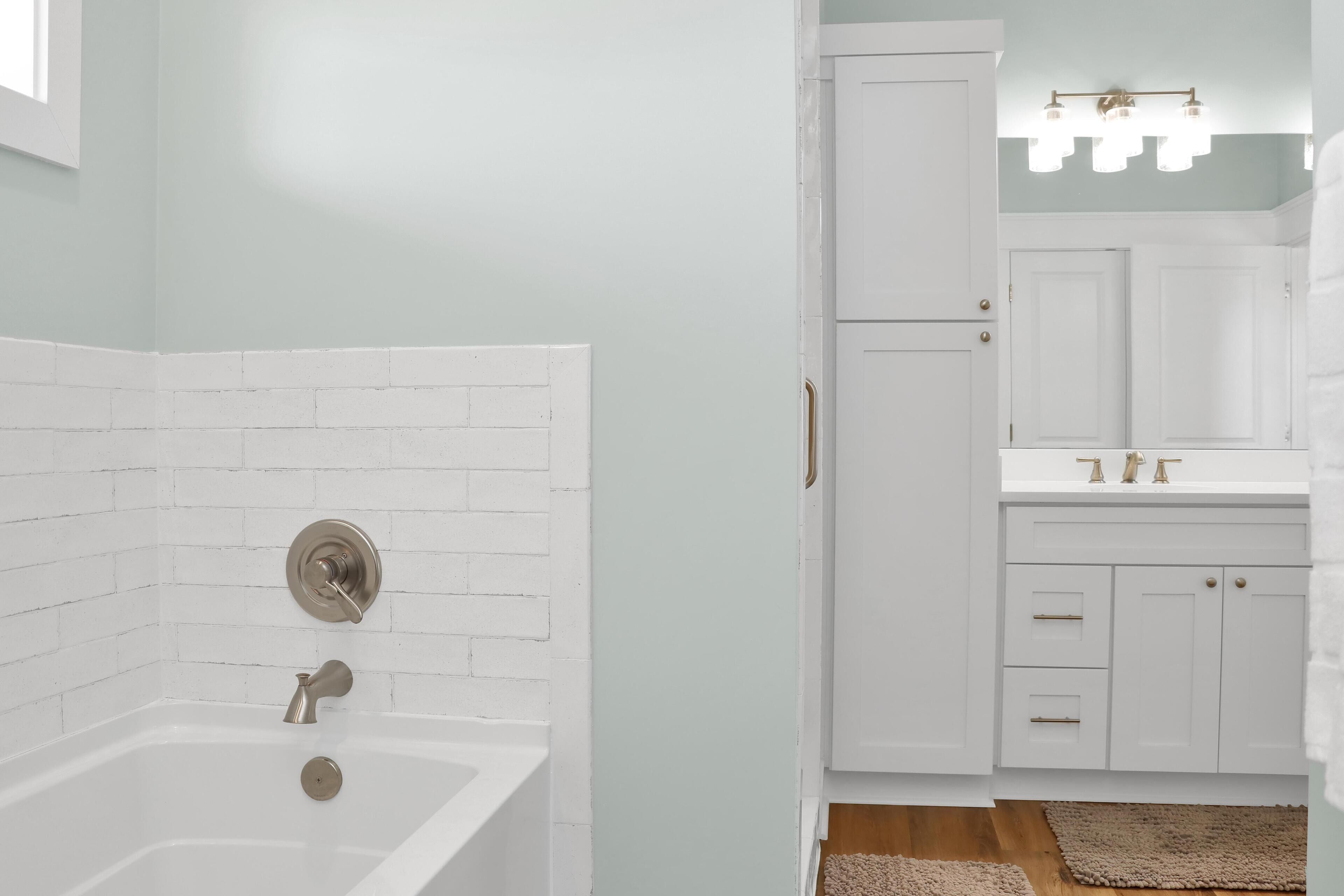 A bathroom with a white bathtub, a white sink with gold fixtures, and a mirror above the sink.