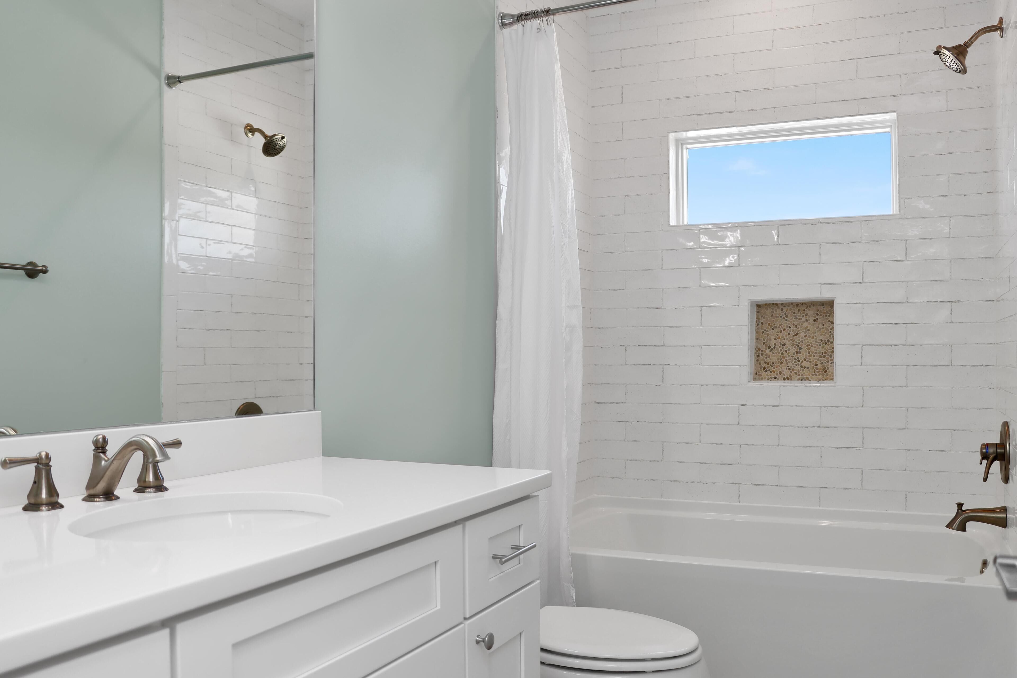 A bathroom with a white sink, vanity, and bathtub.