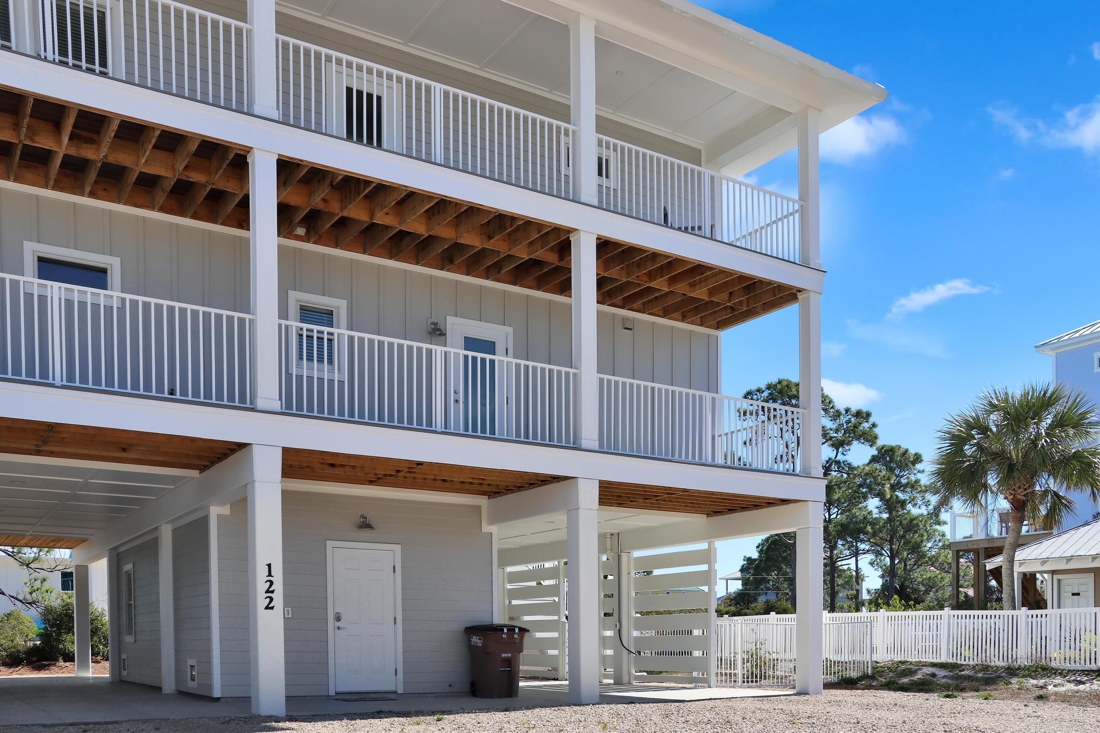 A two-story building with a covered porch and a white fence.