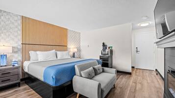 A modern hotel room with a bed, a sofa, a desk, and a TV.