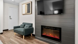 Una sala de estar moderna con chimenea, un sofá y un televisor montado en la pared.