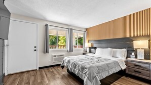 Un dormitorio moderno con una cama grande, un panel de madera en la pared y una ventana con cortinas.