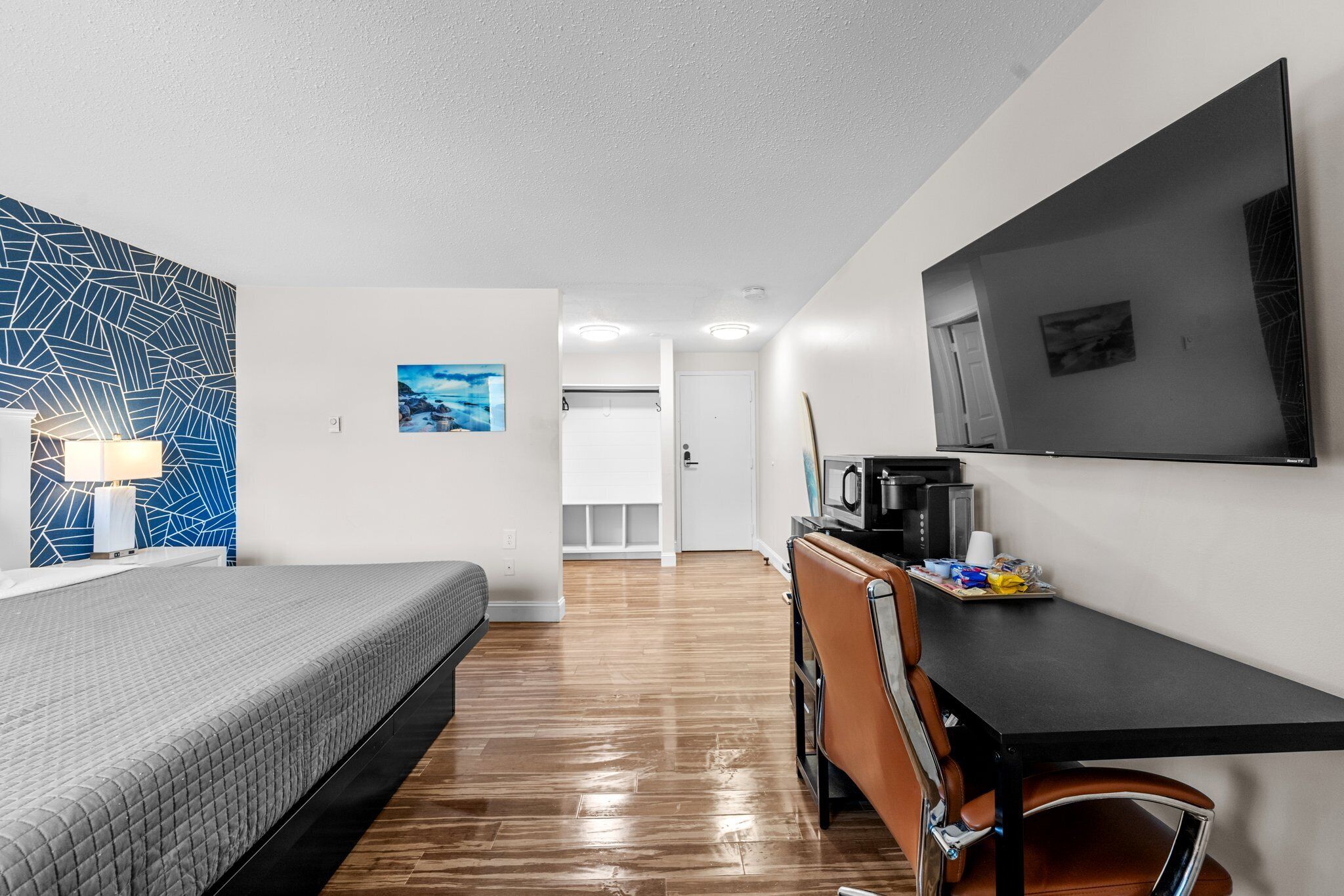 Hotellihuone, jossa on sänky, työpöytä tuolilla, televisio ja mikroaaltouuni.