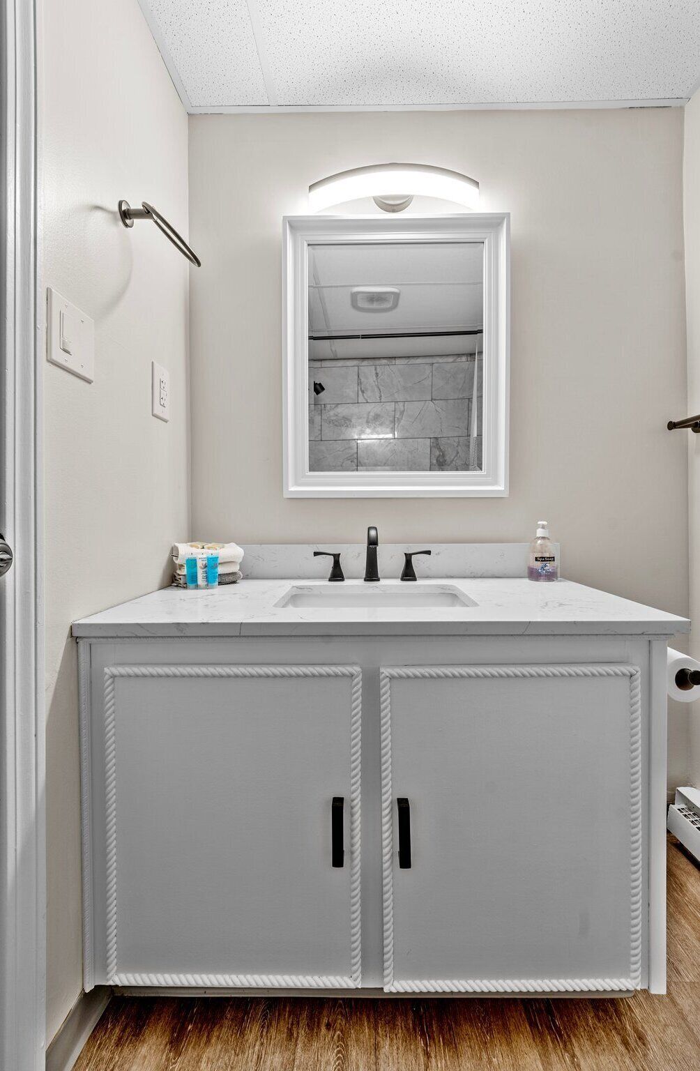A bathroom with a white vanity, a mirror, and a shower visible through the glass door.