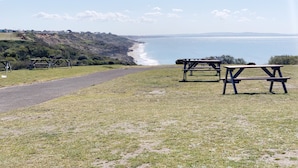 Eine Küstenansicht mit Picknicktischen und einem Weg zum Strand.