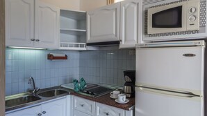 A kitchen with white cabinets, a microwave, a coffee maker, and a sink. - Alsol Patricio (San Bartolomé de Tirajana)