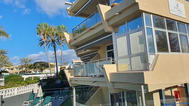 A modern hotel with a pool, outdoor seating, and palm trees. - Alsol Patricio (San Bartolomé de Tirajana)