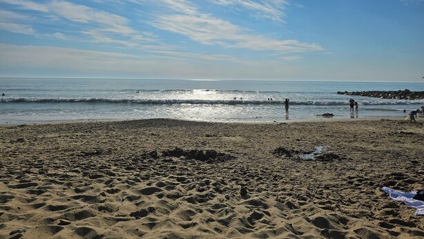A beach with waves, a clear sky, and people. - A 15 Minutes des Plages, Maison de Ville Avec Petit Jardin Pour 8 Personnes (Lesparre-Médoc)