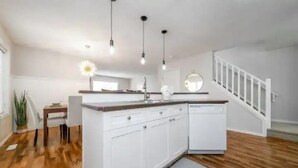 A modern kitchen with white cabinetry, a wooden countertop, and pendant lighting. - Luxurious & Cozy-5bdrm Home-Minutes to WEM-WIFI (Edmonton)
