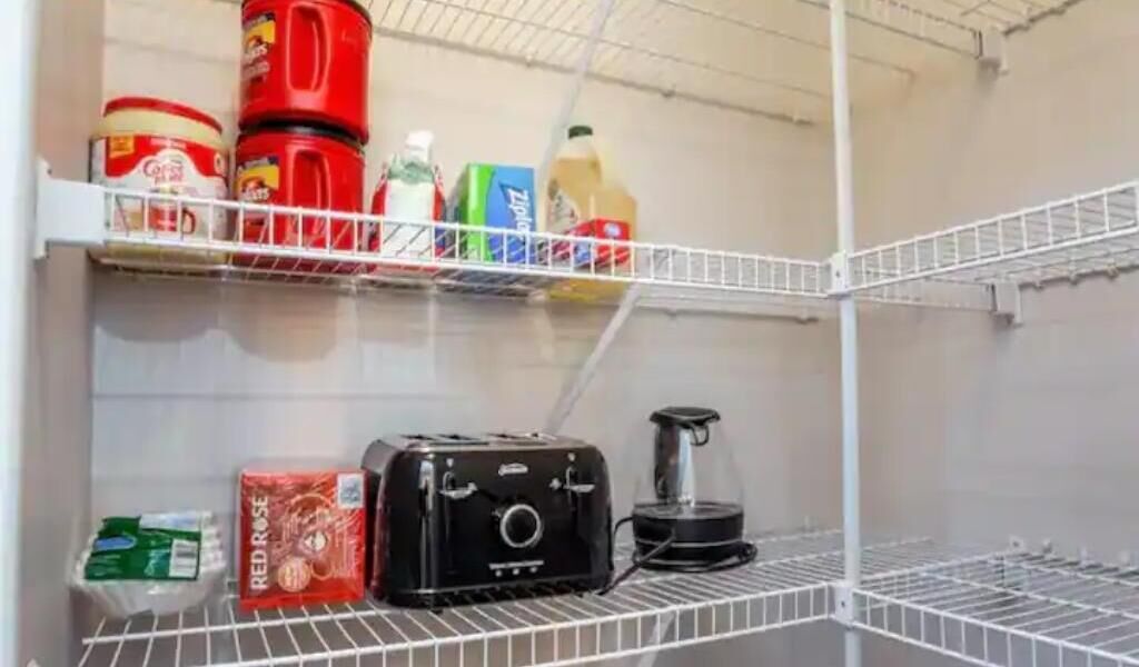 Un área de almacenamiento con estantes que contienen diversos alimentos y una cafetera.