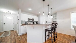 A modern kitchen with white cabinets, a central island, and pendant lighting. - Luxurious & Cozy-5bdrm Home-Minutes to WEM-WIFI (Edmonton)
