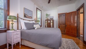 Une chambre à coucher avec un lit, une table de chevet, une commode et une porte en bois.