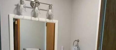 Un baño con tocador blanco, un espejo grande y un perchero para toallas.