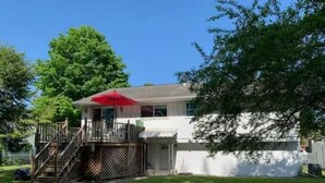 A single-story house with a front deck and a red umbrella.