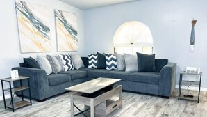 Un salon moderne avec un canapé d’angle, une table basse et une table d’appoint.