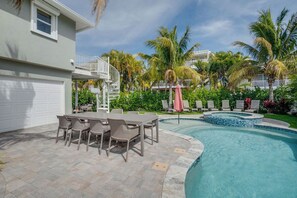 A residential property with a swimming pool, outdoor seating, and a two-story building.