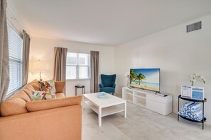 En moderne stue med sofa, sofabord, fjernsyn og et lille sidebord.