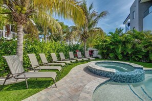 A pool area with lounge chairs and palm trees.