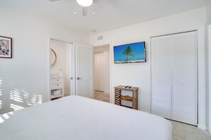 A bedroom with a bed, a TV, a wardrobe, and a door leading to another room.