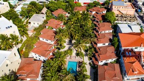 Oversigtsbillede af et resort med flere bygninger, palmer og en swimmingpool.