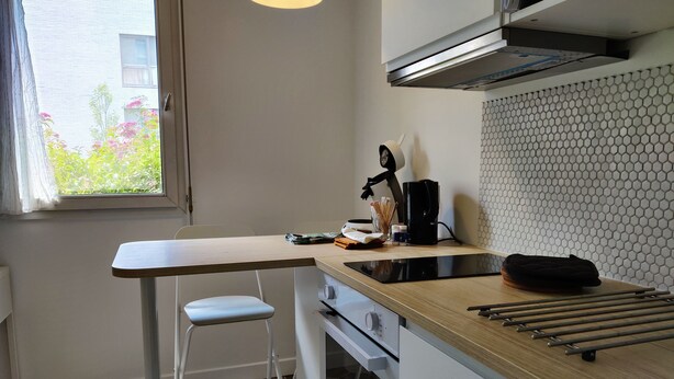 A modern kitchen with a wooden countertop, a built-in oven, and a window with a view of greenery.