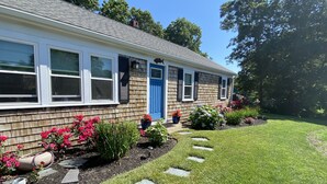 Una casa a due piani con una porta blu, finestre bianche e un giardino con pietre che formano un sentiero verso l'ingresso.