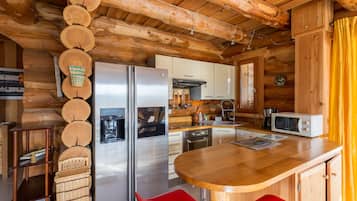 A wooden cabin kitchen with a central island, stainless steel appliances, and a dining area.