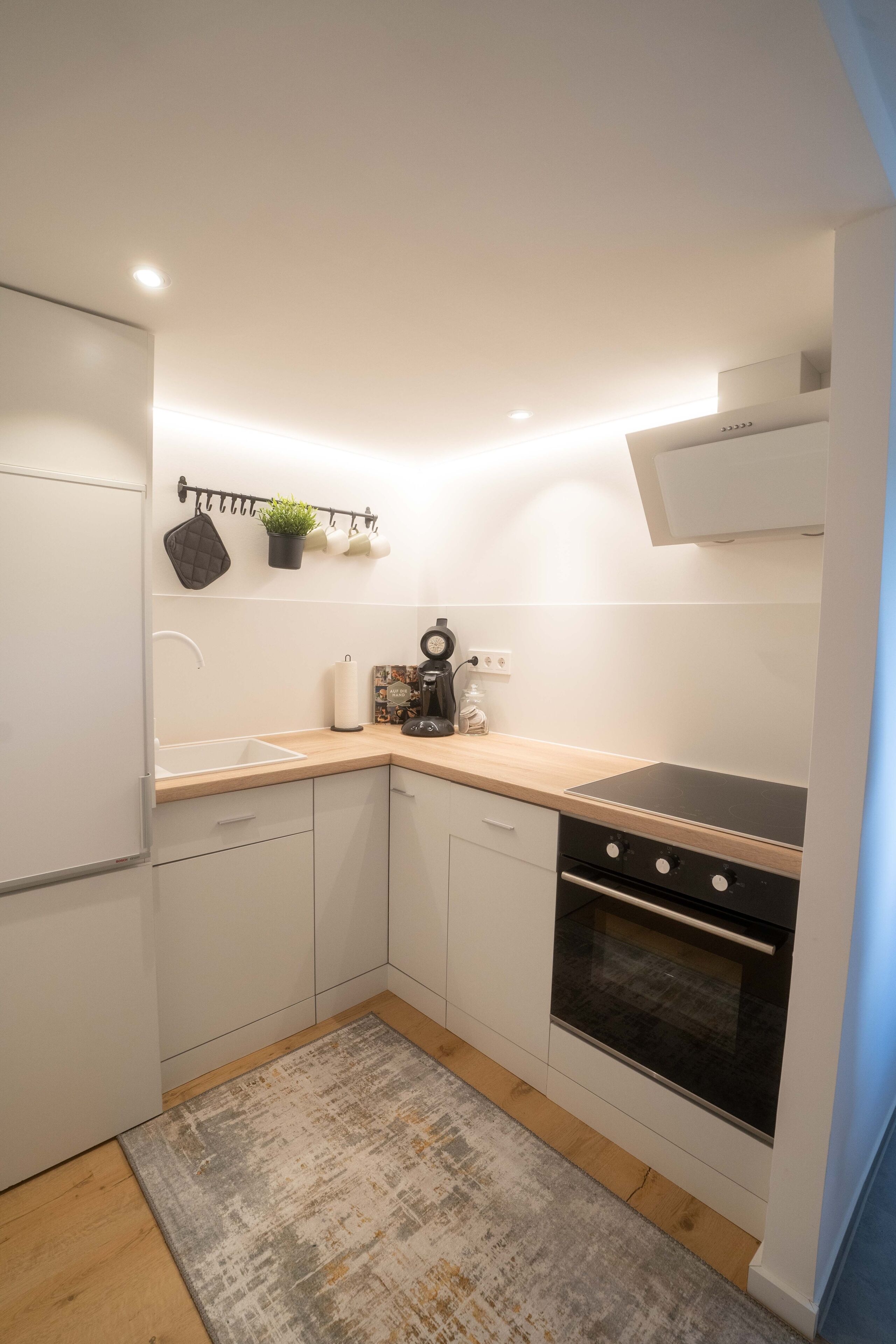 A compact kitchen with white cabinets, a black stove, and a wooden countertop.