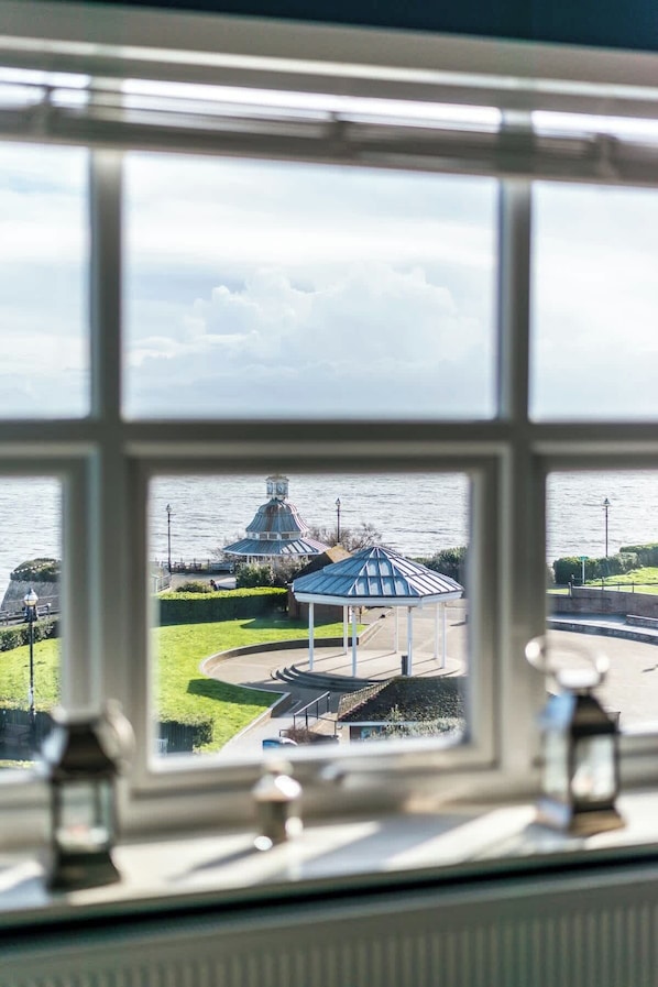 A view through a window of a gazebo, a lamp post, and a body of water.