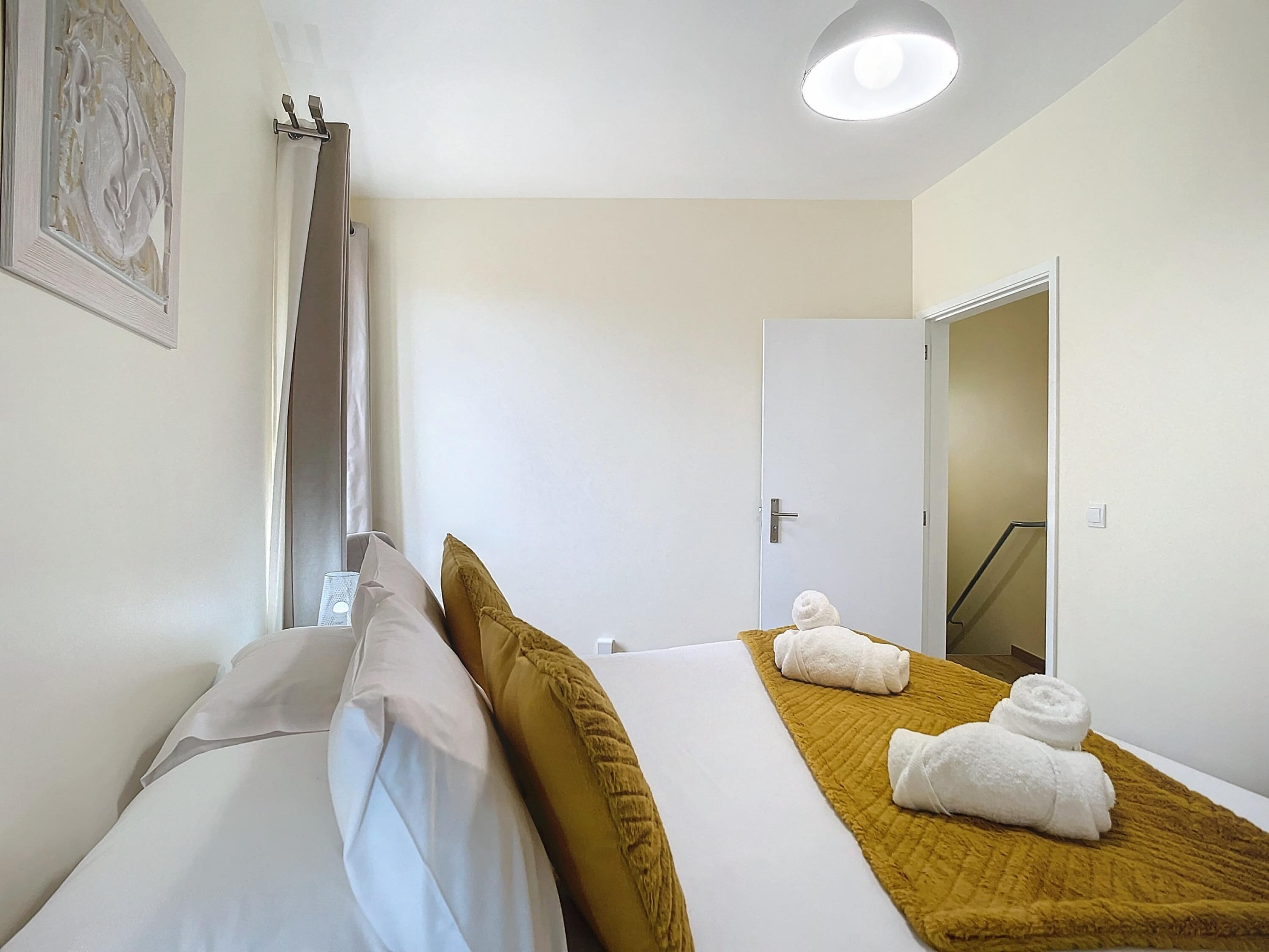 Ein Hotelzimmer mit einem Bett, einem Fenster mit Vorhang, einer Tür und einem Handtuch auf dem Bett.