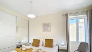 Ett modernt hotellrum med en stor säng, sängbord med lampor, en stol och ett fönster med gardiner.
