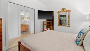 A bedroom with a bed, a television, a mirror, and a wardrobe.