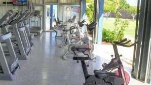 A row of stationary bikes in a covered area with a view of greenery outside.