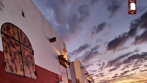 Un bâtiment à la façade rouge et blanche, avec une porte en bois et un escalier menant à l’entrée.