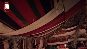 Un espace de restauration aménagé sous une tente, avec des tables dressées pour le repas, agrémenté de nappes à rayures et d’une variété de plats.