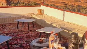 Une terrasse aménagée avec un espace repas comprenant une table, des chaises et une variété de plats.