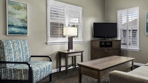 A living room with a television, a small table, a chair, and a sofa.