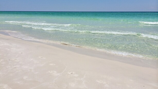 A beach with clear turquoise water and a sandy shore.