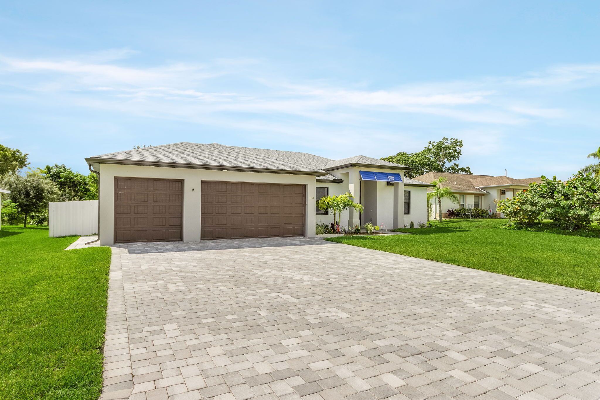 A residential house with a paved driveway, two garage doors, and a well-maintained lawn.
