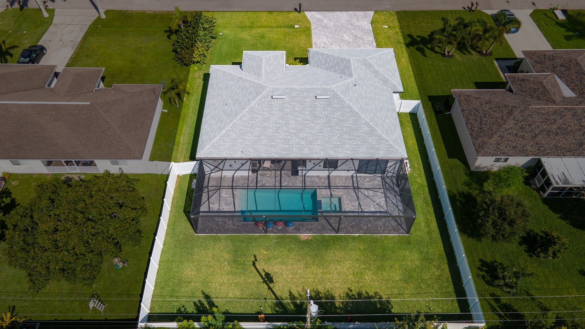 An aerial view of a building with a swimming pool, surrounded by well-maintained lawns and neighboring houses.
