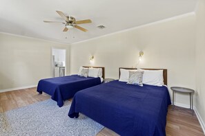 Une chambre avec deux lits, un ventilateur de plafond et une petite table.