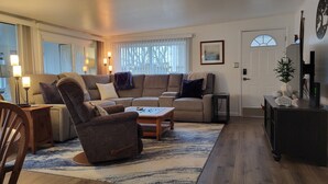 Een gezellige woonkamer met een bank, fauteuil en salontafel, een eetgedeelte met een tafel en stoelen, en een decor kast.