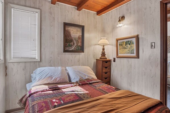 Une chambre à coucher avec un lit, une table de chevet avec une lampe et deux tableaux encadrés accrochés au mur.