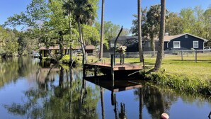 A serene lakeside property with a dock, a house, and a fenced area. - Have it all at this beautiful waterfront Homosassa home close to all amenities. (Homosassa)