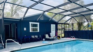 A swimming pool with a covered area, chairs, and a fenced yard. - Have it all at this beautiful waterfront Homosassa home close to all amenities. (Homosassa)