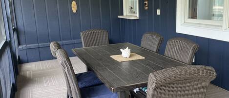 A dining area with a dark wooden table, wicker chairs, and a ceiling fan.