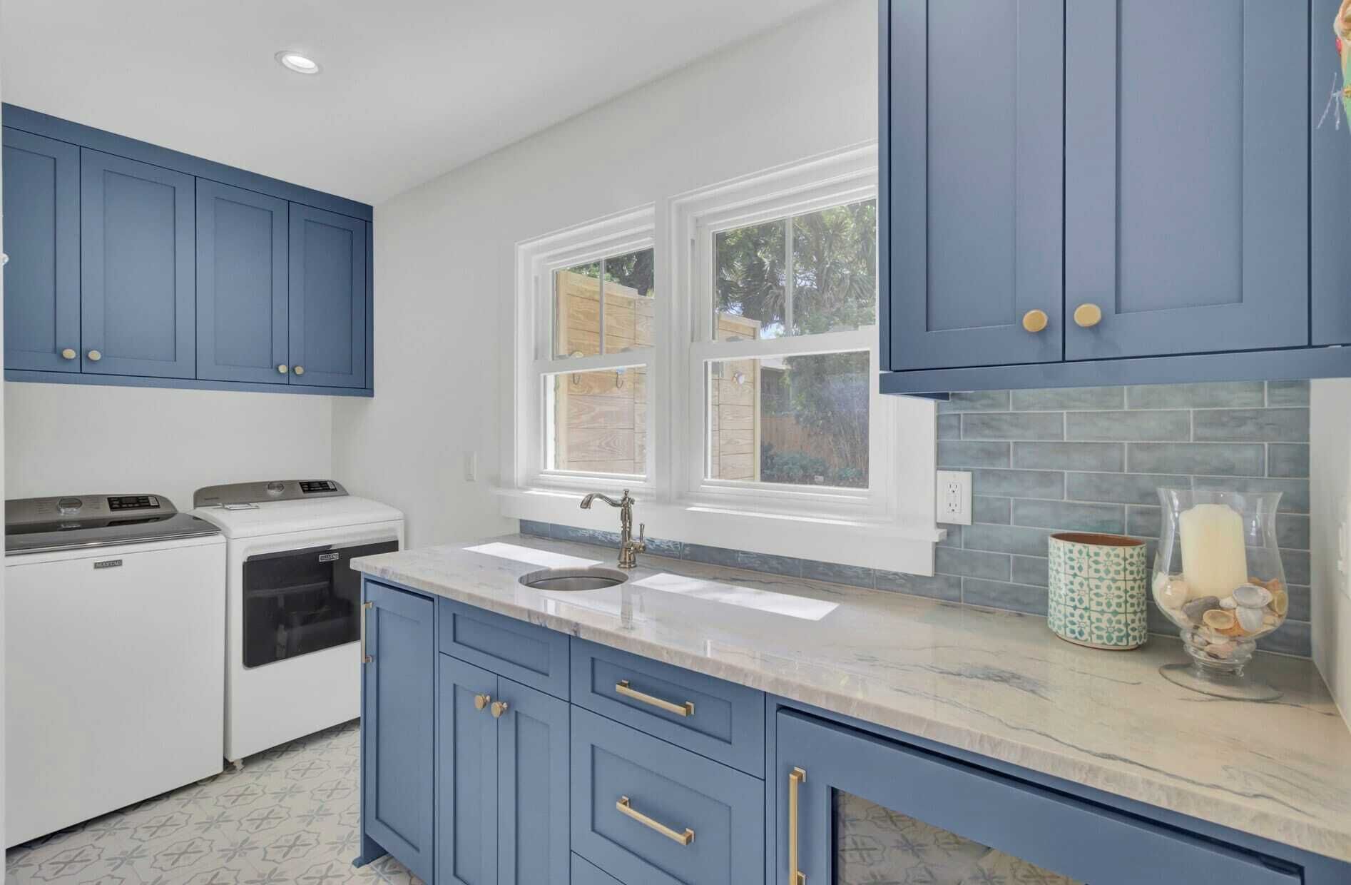 A kitchen with blue cabinets, a white stove, and a window with a view of greenery outside.
