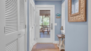 A hallway with white doors, a wooden bench outside, a table, and a mirror on the wall. - 29 24th Avenue by Avantstay Easy Beach Access (Isle of Palms)