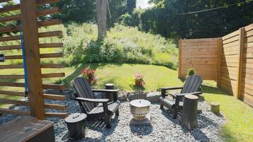 Un patio con sillas tipo Adirondack, una fogata y un cerco de madera.